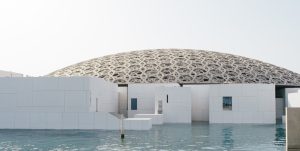 Image depicting the iconic architecture of Louvre Abu Dhabi against a blue sky, inviting travelers to explore the museum's cultural treasures in 2023.